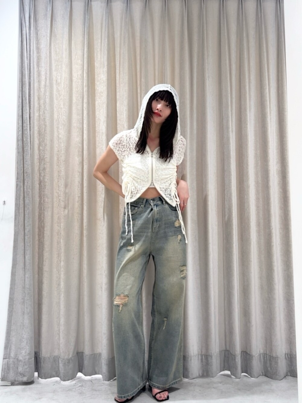 ホワイト系のパーカー、ブルー系のデニムパンツ、シルバー系のサンダルを着用したレディースの夏コーディネートの2枚目の写真