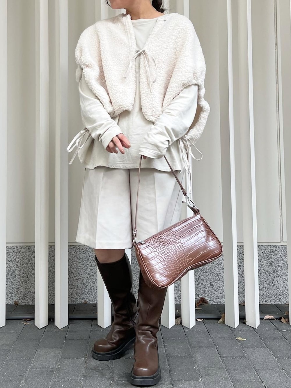 ホワイト系のブルゾン、グレー系のTシャツ/カットソー、ブラウン系のブーツを着用したレディースの秋コーディネートの2枚目の写真