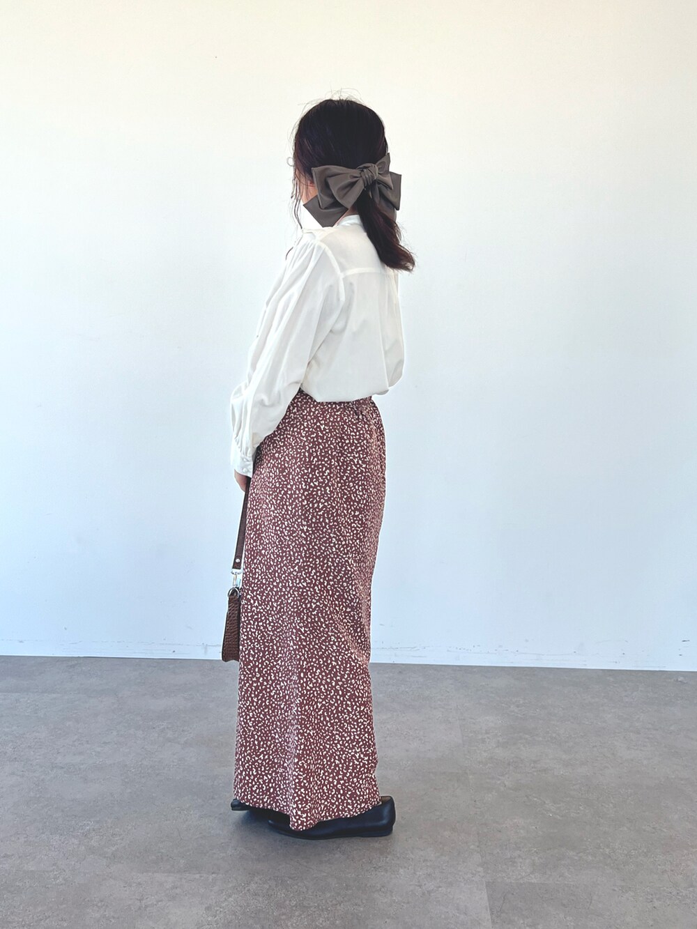 ホワイト系のシャツ/ブラウス、ブラウン系のスカート、ブラウン系のバレッタ/ヘアクリップを着用したレディースの秋コーディネートの2枚目の写真