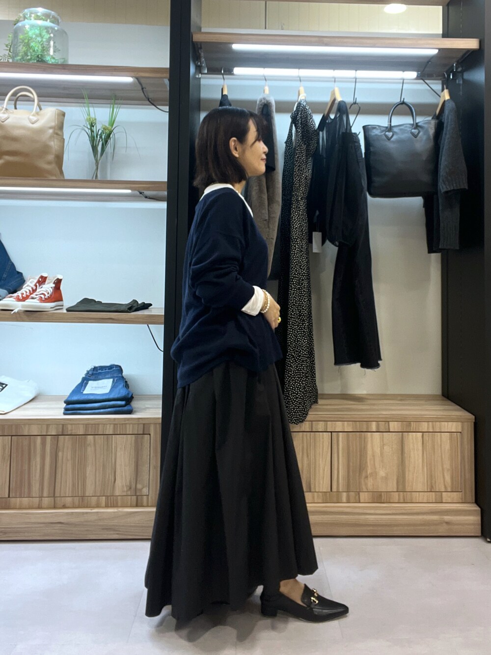 ブルー系のニット/セーター、ホワイト系のTシャツ/カットソー、ブラック系のスカートを着用したレディースの秋コーディネートの2枚目の写真