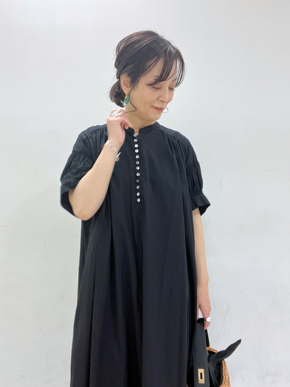 ブラック系のワンピース、イエロー系のかごバッグ、ブラック系のサンダルを着用したレディースの春コーディネートの3枚目の写真