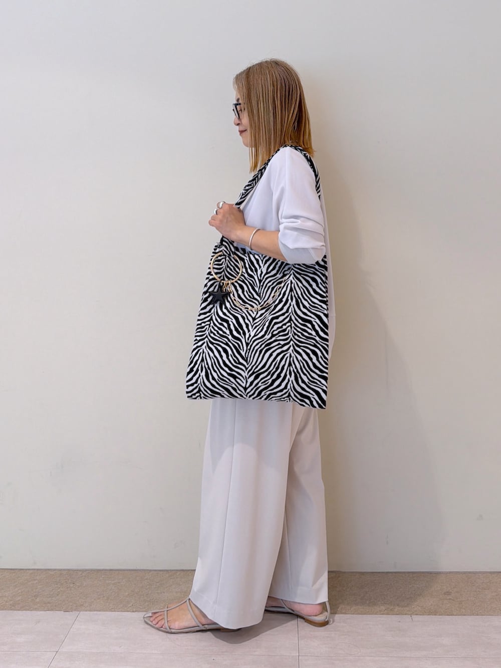 ベージュ系のスラックス、グレー系のシャツ/ブラウス、ブラック系のトートバッグを着用したレディースの夏コーディネートの2枚目の写真