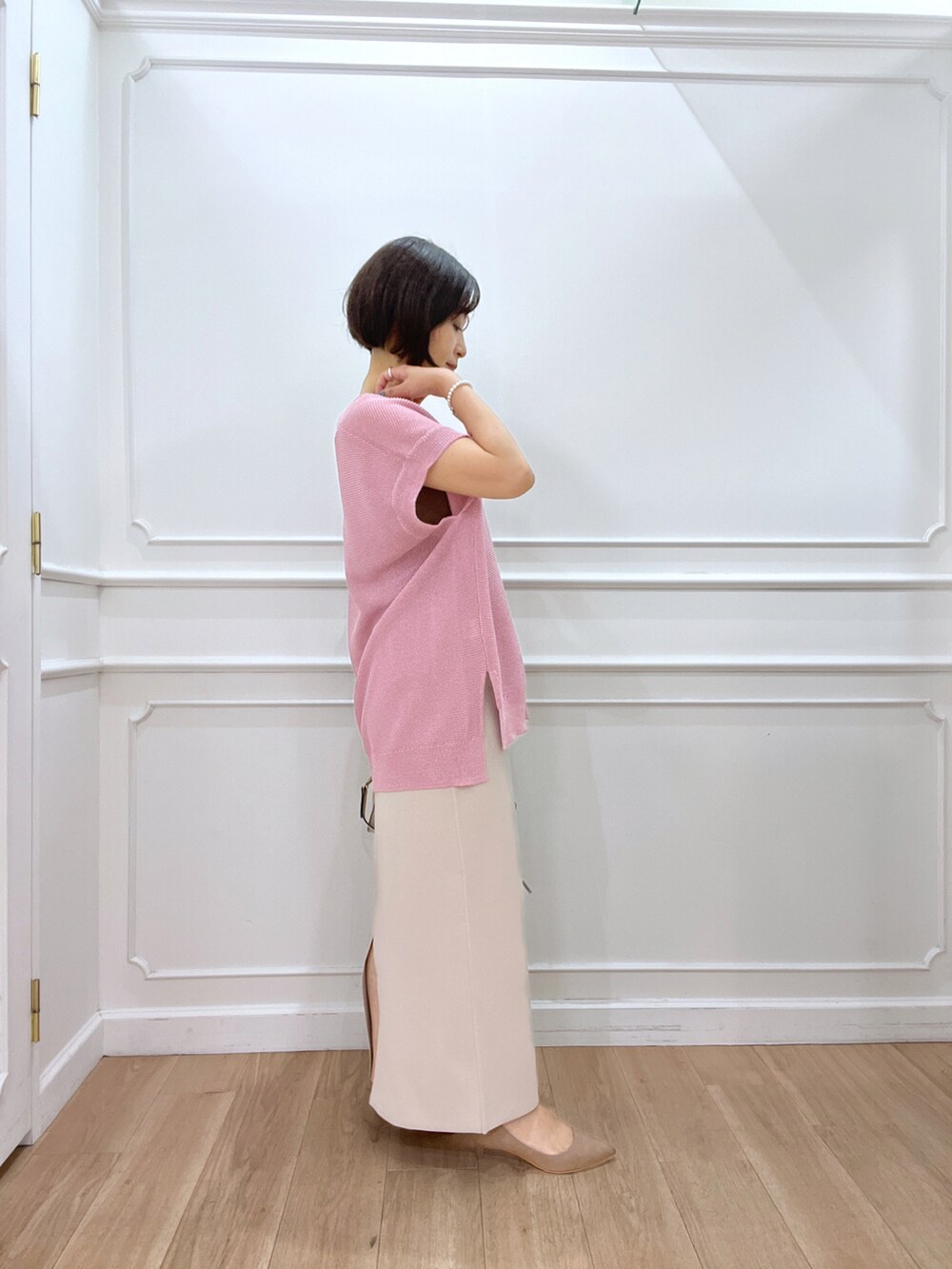 ピンク系のニット/セーター、ベージュ系のスカート、ホワイト系のショルダーバッグを着用したレディースの夏コーディネートの2枚目の写真