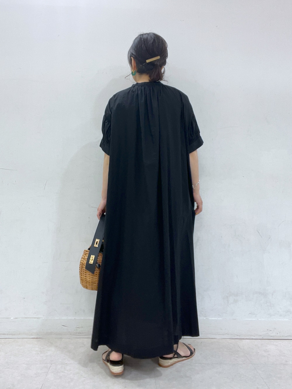 ブラック系のワンピース、イエロー系のかごバッグ、ブラック系のサンダルを着用したレディースの春コーディネートの2枚目の写真