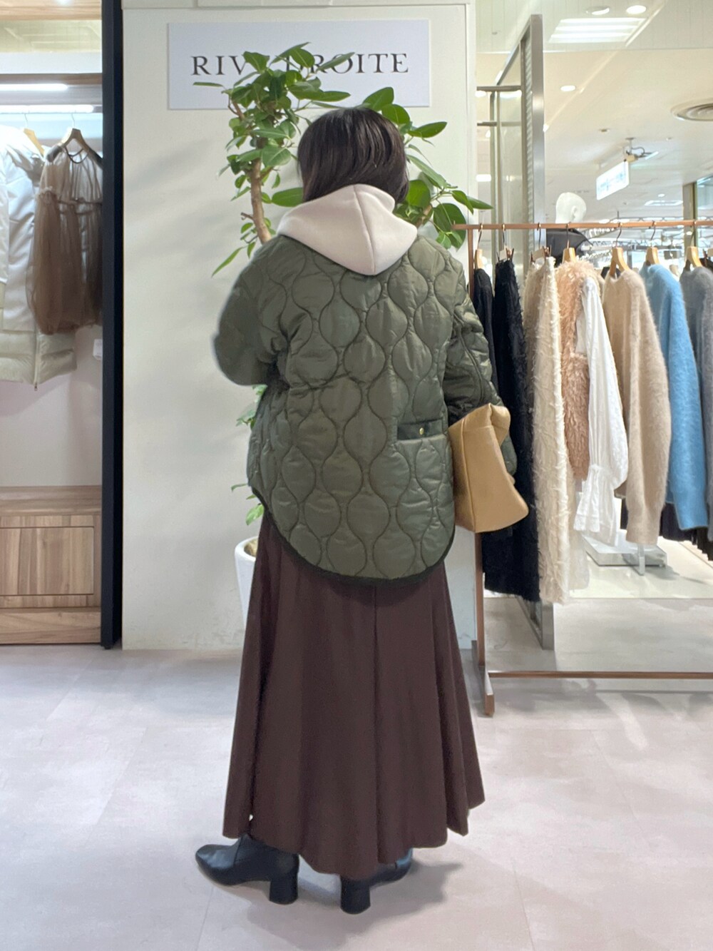グリーン系のダウンジャケット/コート、ホワイト系のニット/セーター、ベージュ系のパーカーを着用したレディースの秋コーディネートの3枚目の写真