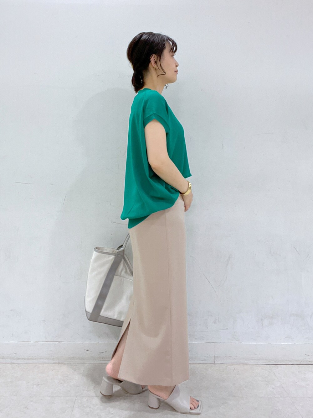 グリーン系のニット/セーター、グレー系のトートバッグ、ベージュ系のスカートを着用したレディースの春コーディネートの2枚目の写真