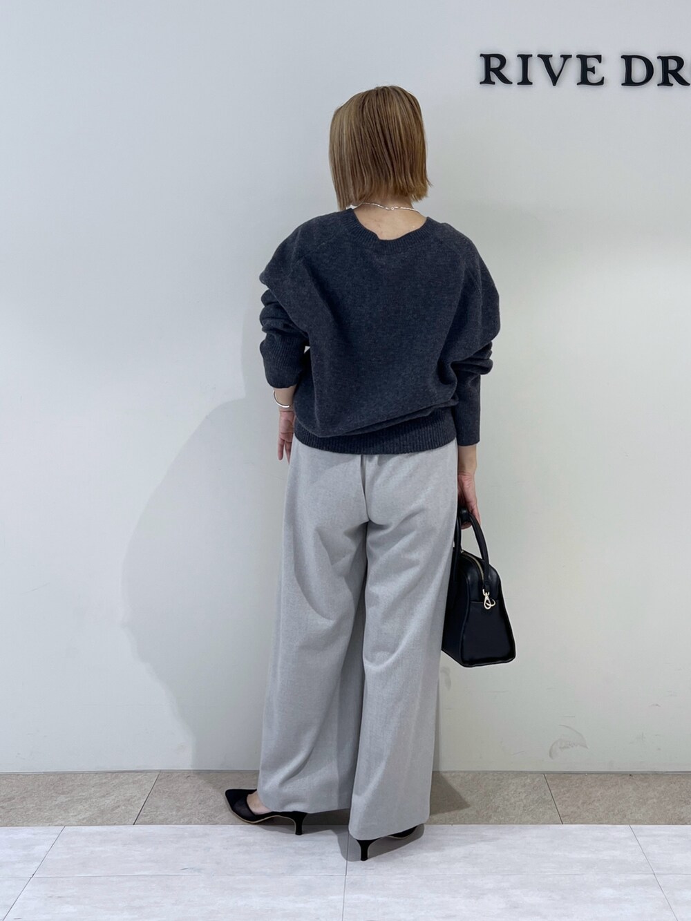 グレー系のニット/セーター、ブラック系のパンプス、ブラック系のボストンバッグを着用したレディースの冬コーディネートの3枚目の写真