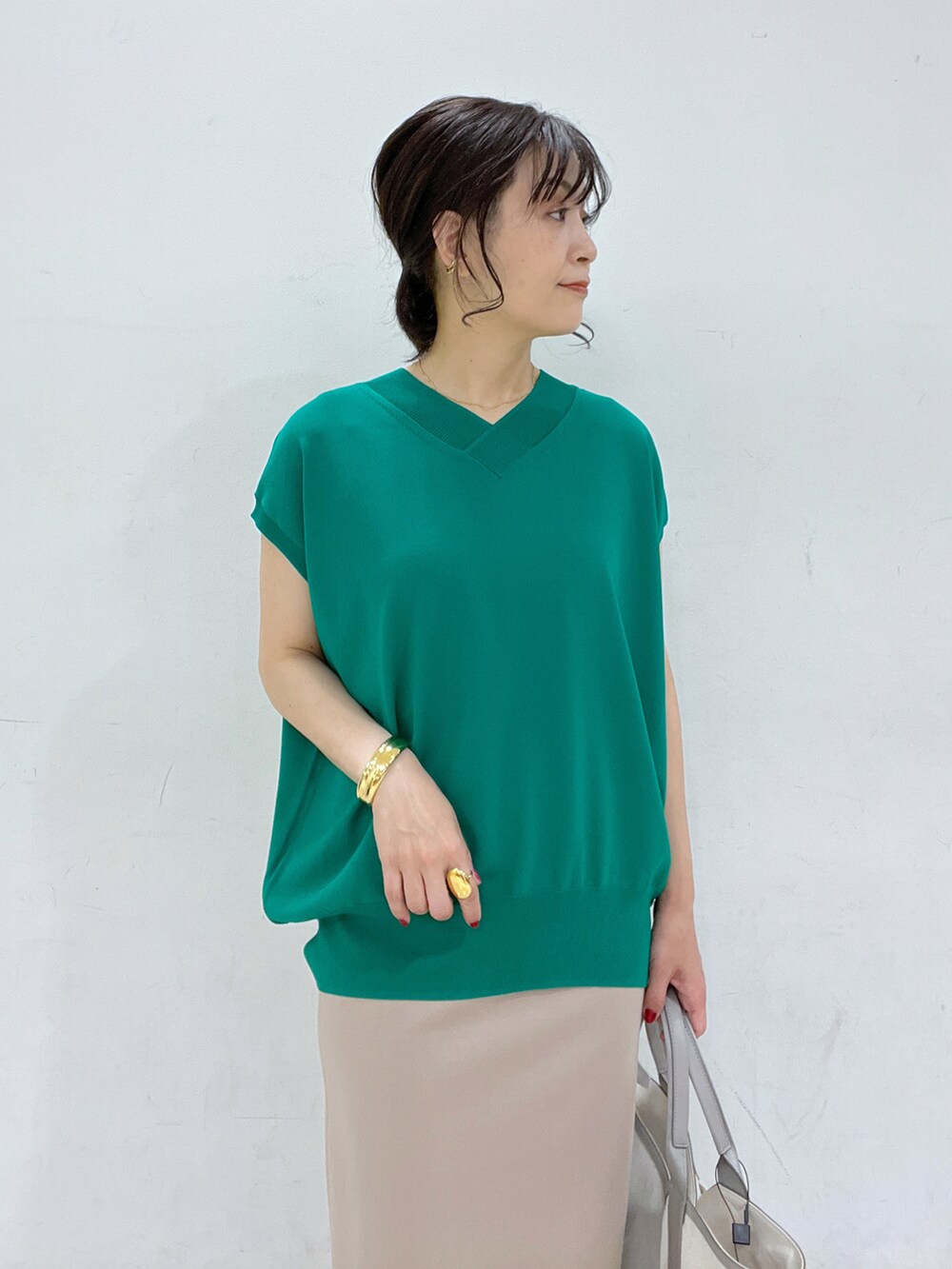 グリーン系のニット/セーター、グレー系のトートバッグ、ベージュ系のスカートを着用したレディースの春コーディネートの4枚目の写真