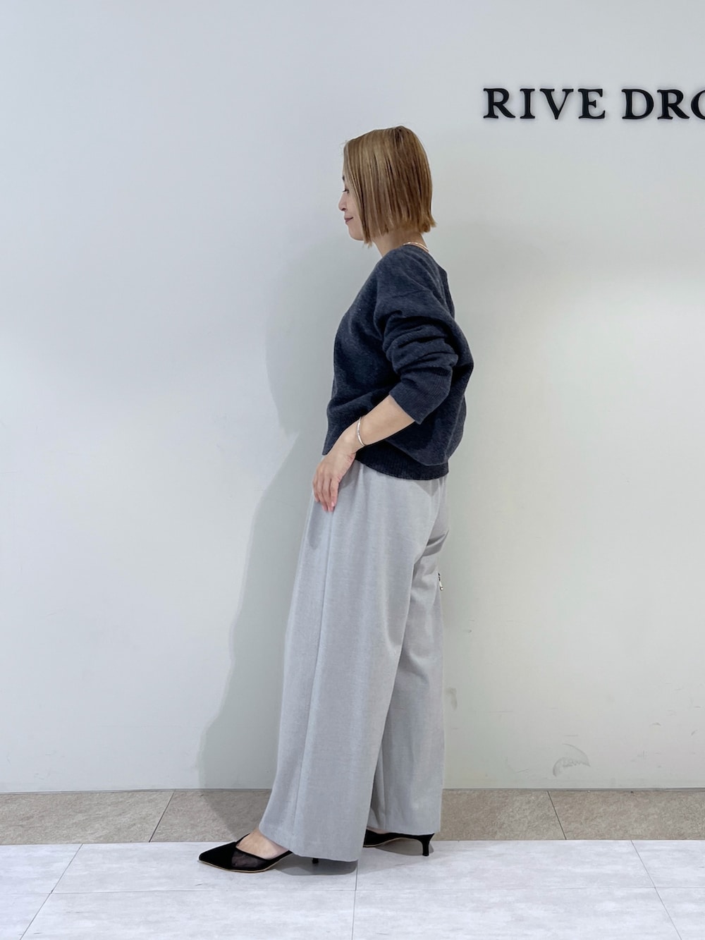 グレー系のニット/セーター、ブラック系のパンプス、ブラック系のボストンバッグを着用したレディースの冬コーディネートの2枚目の写真