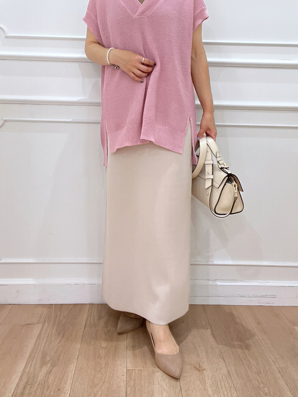 ピンク系のニット/セーター、ベージュ系のスカート、ホワイト系のショルダーバッグを着用したレディースの夏コーディネートの4枚目の写真