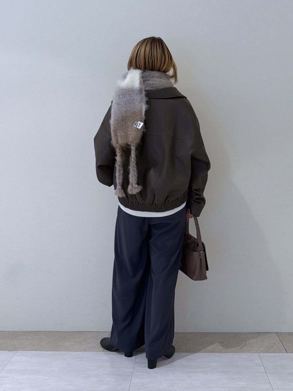 ブラウン系のブルゾン、ブラック系のブーツ、グレー系のスラックスを着用したレディースの冬コーディネートの3枚目の写真