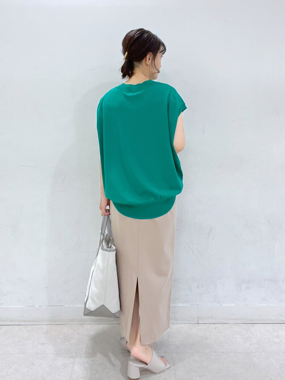 グリーン系のニット/セーター、グレー系のトートバッグ、ベージュ系のスカートを着用したレディースの春コーディネートの3枚目の写真