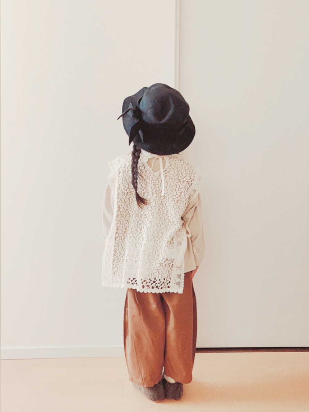 ホワイト系のベスト、ベージュ系のTシャツ/カットソー、ブラウン系のパンツを着用したキッズの冬コーディネートの2枚目の写真