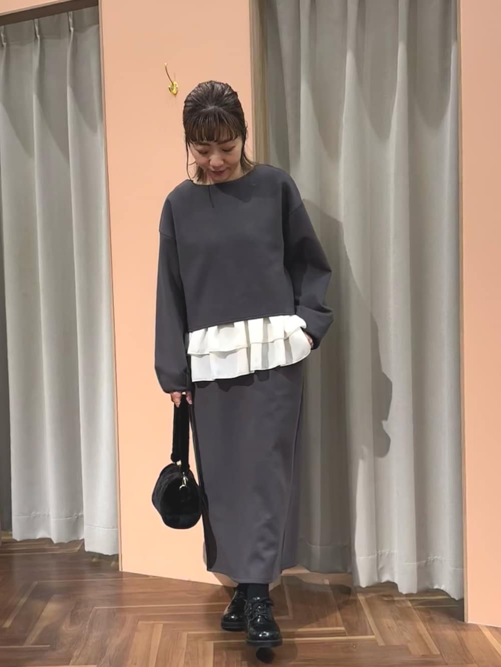 グレー系のTシャツ/カットソー、グレー系のスカート、ブラック系のハンドバッグを着用したレディースの秋コーディネートの4枚目の写真