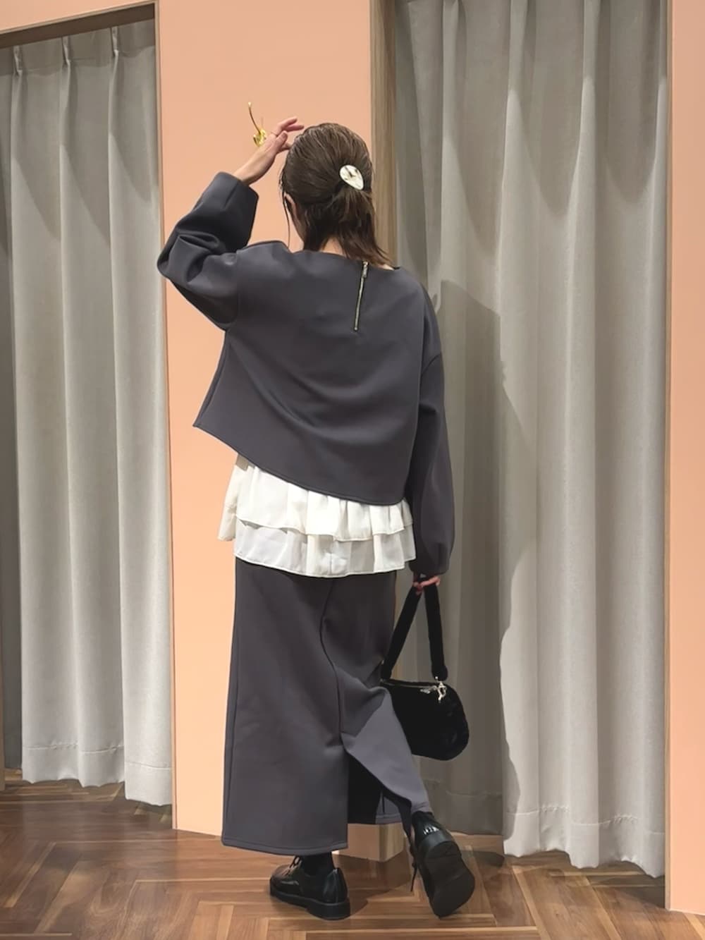 グレー系のTシャツ/カットソー、グレー系のスカート、ブラック系のハンドバッグを着用したレディースの秋コーディネートの3枚目の写真