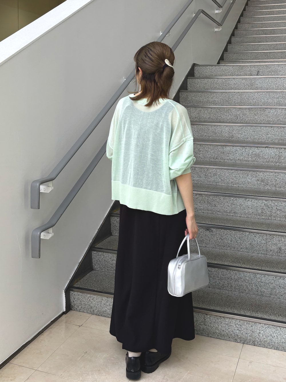 グリーン系のカーディガン/ボレロ、ブラック系のワンピースを着用したレディースの春コーディネートの2枚目の写真