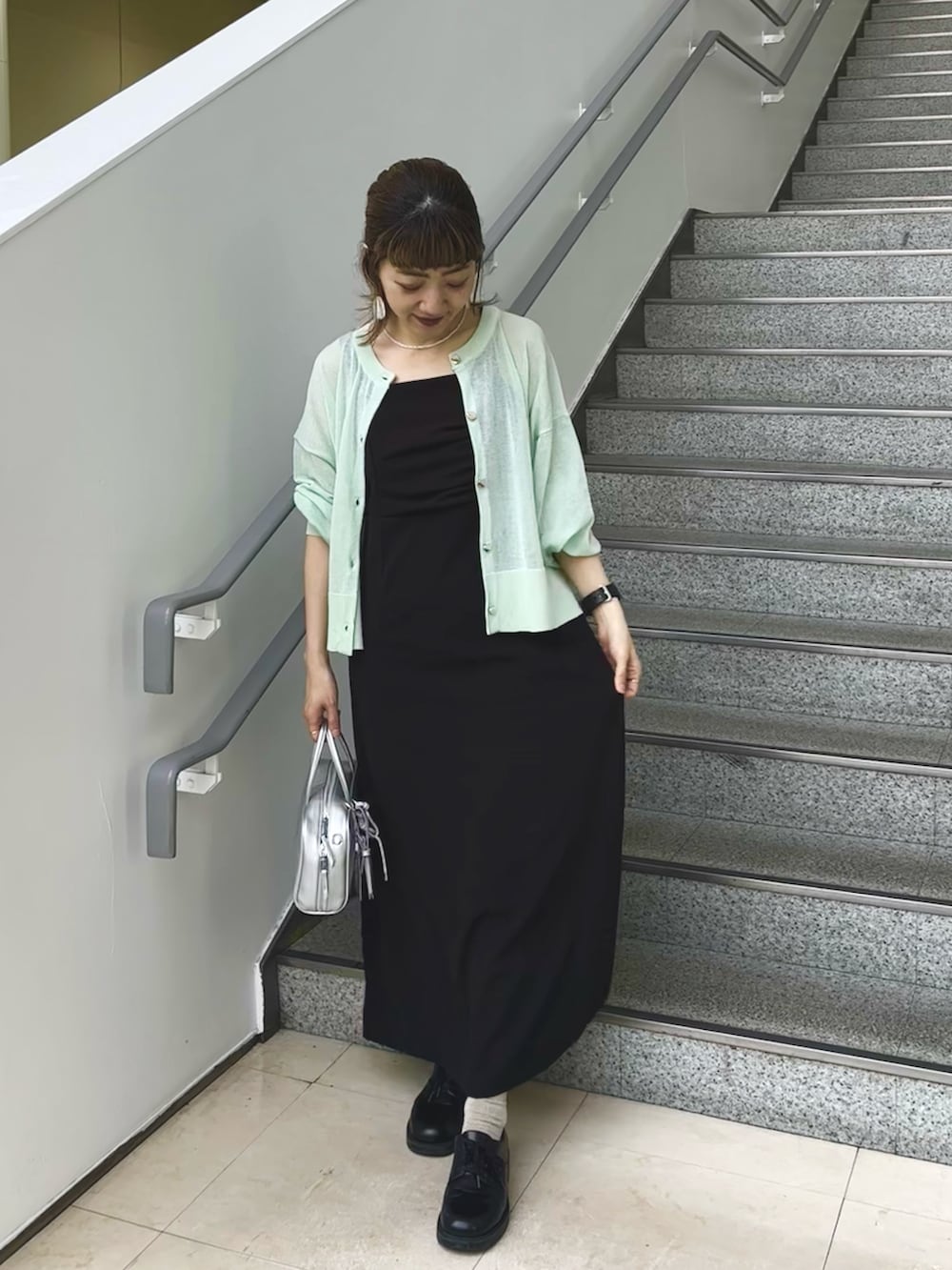グリーン系のカーディガン/ボレロ、ブラック系のワンピースを着用したレディースの春コーディネートの3枚目の写真