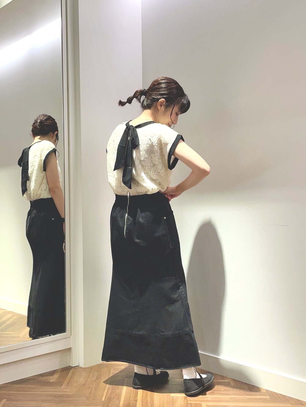 ホワイト系のシャツ/ブラウス、ブラック系のスカート、ブラック系のハンドバッグを着用したレディースの夏コーディネートの2枚目の写真