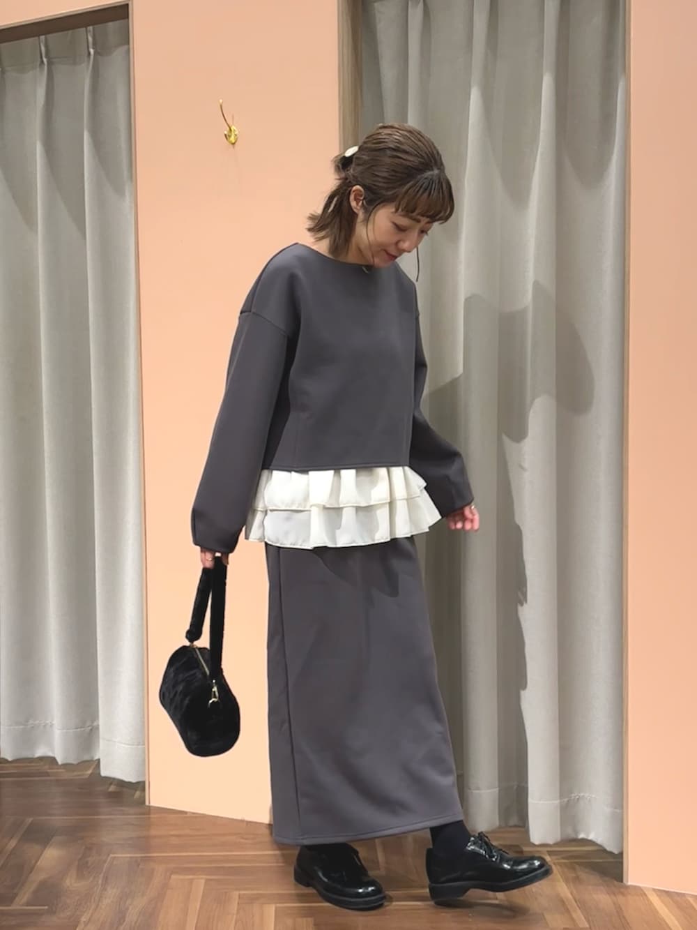 グレー系のTシャツ/カットソー、グレー系のスカート、ブラック系のハンドバッグを着用したレディースの秋コーディネートの2枚目の写真