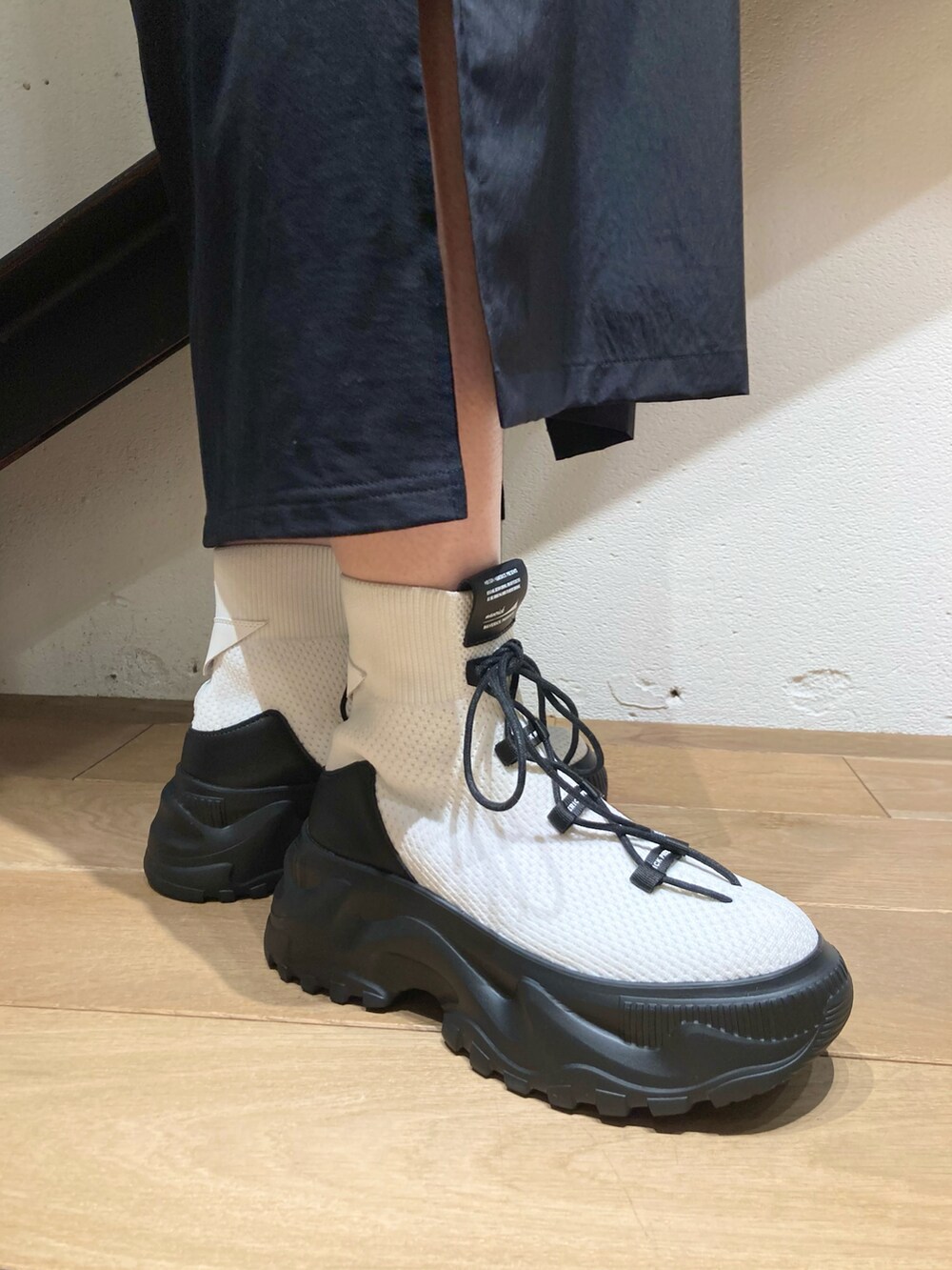 ホワイト系のカーディガン/ボレロ、ブラック系のワンピース、ホワイト系のスニーカーを着用したレディースの冬コーディネートの3枚目の写真