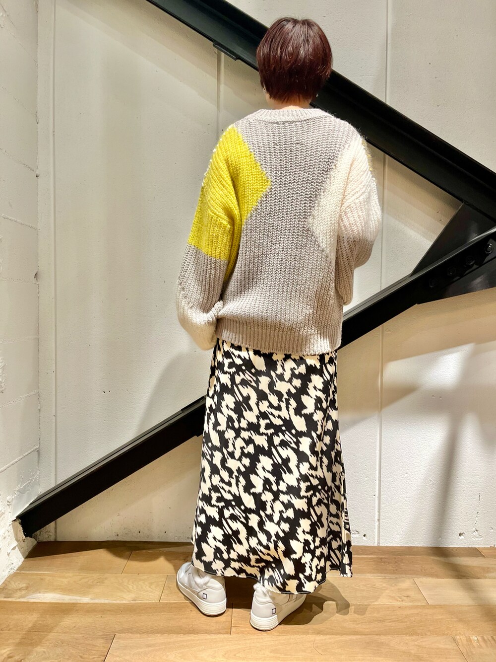 グレー系のバッグ、グレー系のニット/セーター、ブラック系のスカートを着用したレディースの秋コーディネートの2枚目の写真