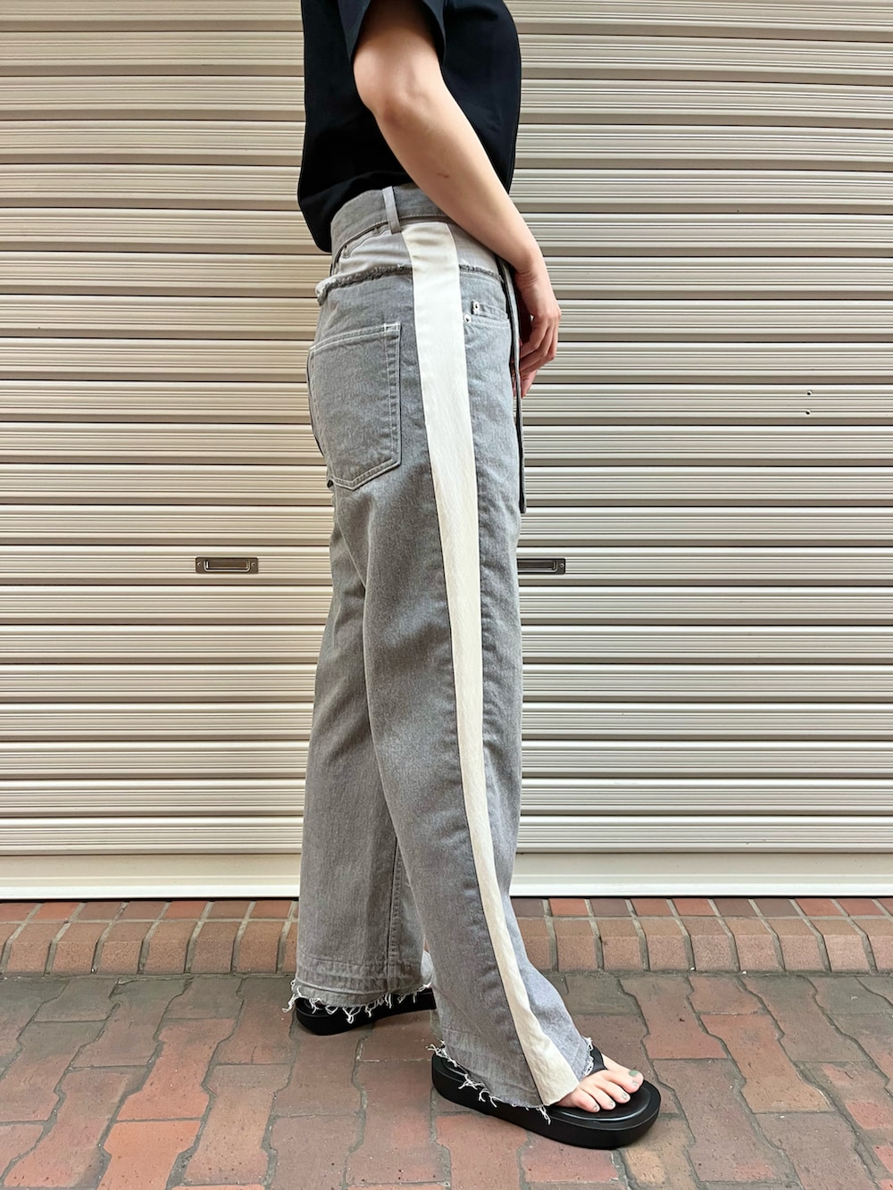 ブラック系のサンダル、グレー系のデニムパンツ、ブラック系のTシャツ/カットソーを着用したレディースの春コーディネートの3枚目の写真