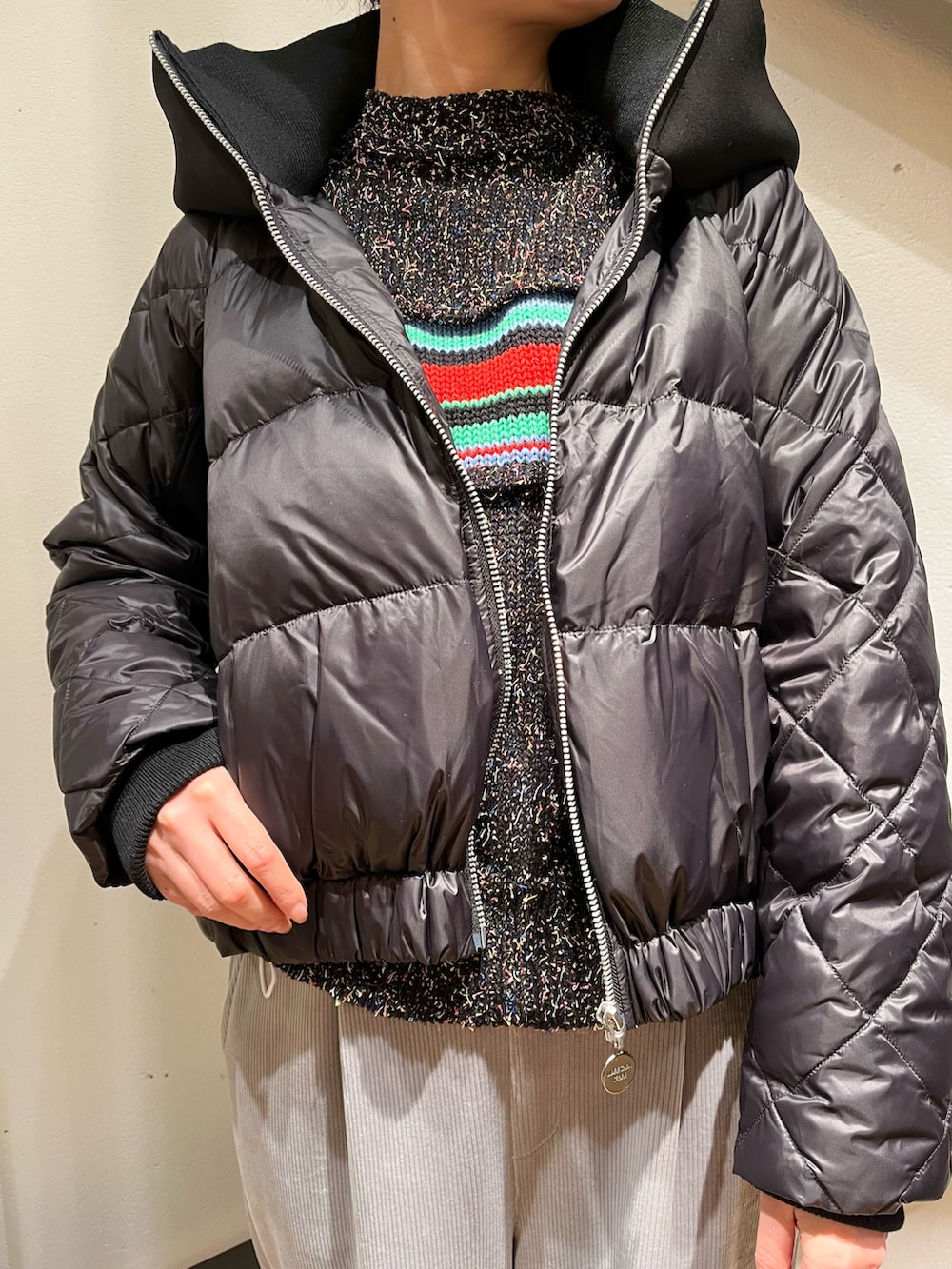 グレー系のショルダーバッグ、ブラック系のダウンジャケット/コート、ブラック系のニット/セーターを着用したレディースの冬コーディネートの3枚目の写真