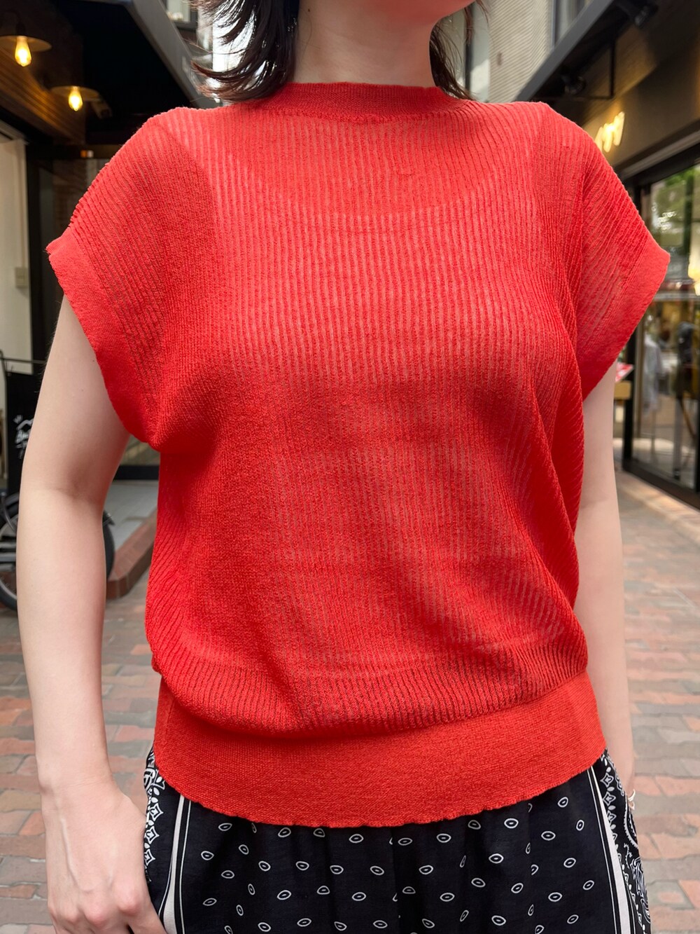 レッド系のニット/セーター、ブラック系のその他パンツ、ホワイト系のサンダルを着用したレディースの夏コーディネートの2枚目の写真