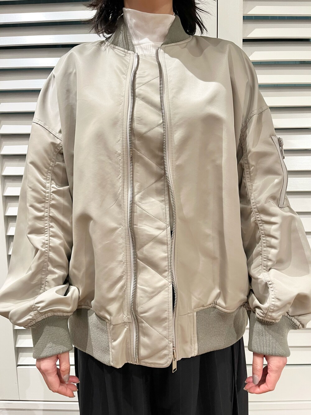 ベージュ系のMA-1、ブルー系のスラックス、ホワイト系のスニーカーを着用したレディースの冬コーディネートの2枚目の写真