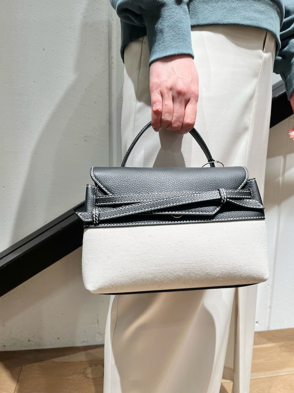 ブラック系のハンドバッグ、グリーン系のスウェット、ホワイト系のスカートを着用したレディースの春コーディネートの2枚目の写真