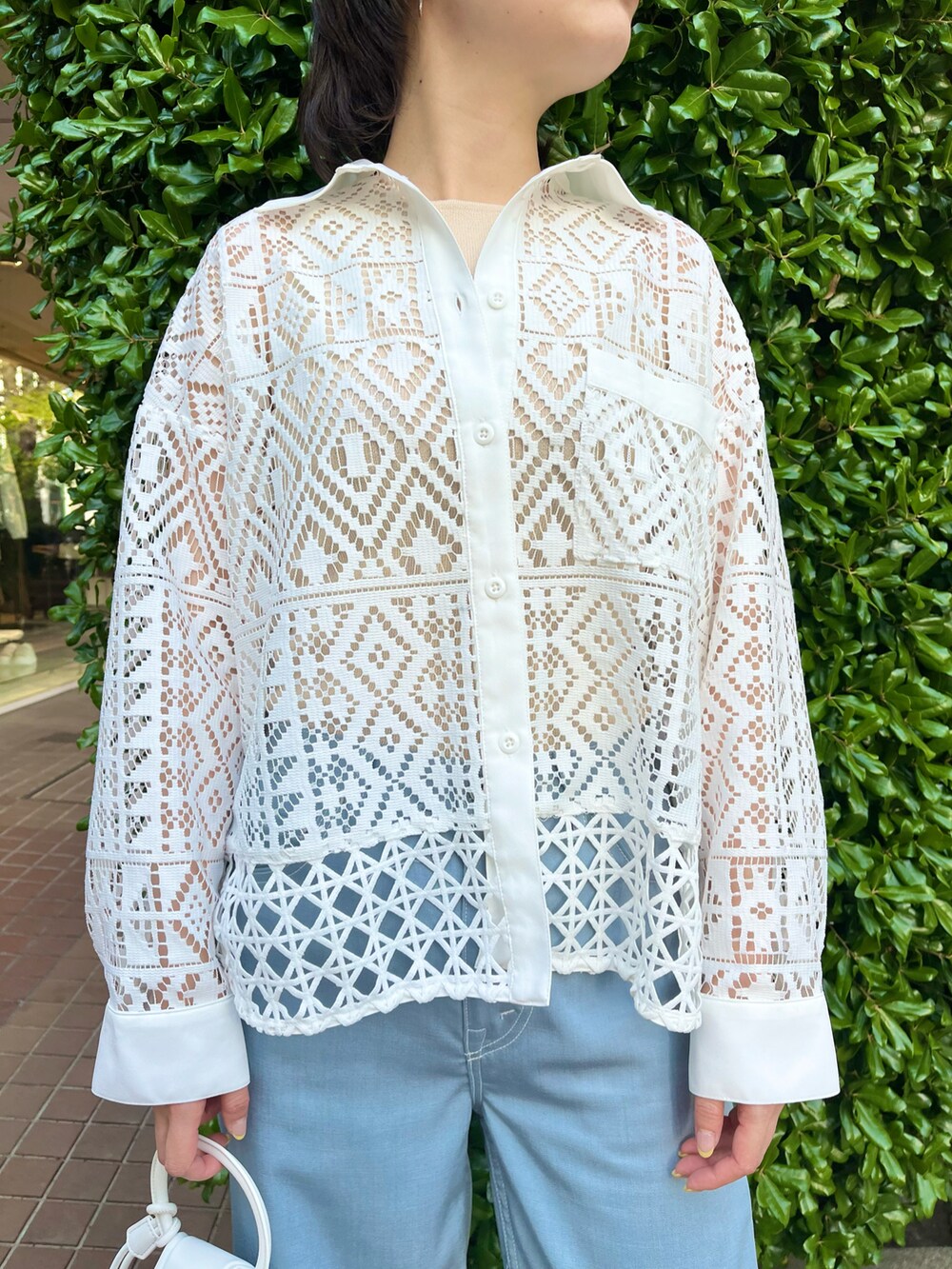 ホワイト系のシャツ/ブラウス、ホワイト系のショルダーバッグ、ブルー系のパンツを着用したレディースの春コーディネートの2枚目の写真