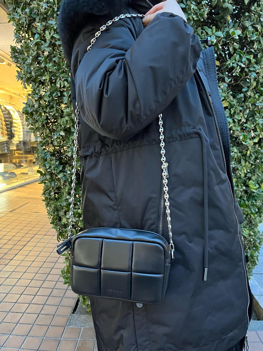 ブラック系のショルダーバッグ、ブラック系のワンピース、ブラック系のスニーカーを着用したレディースの冬コーディネートの2枚目の写真