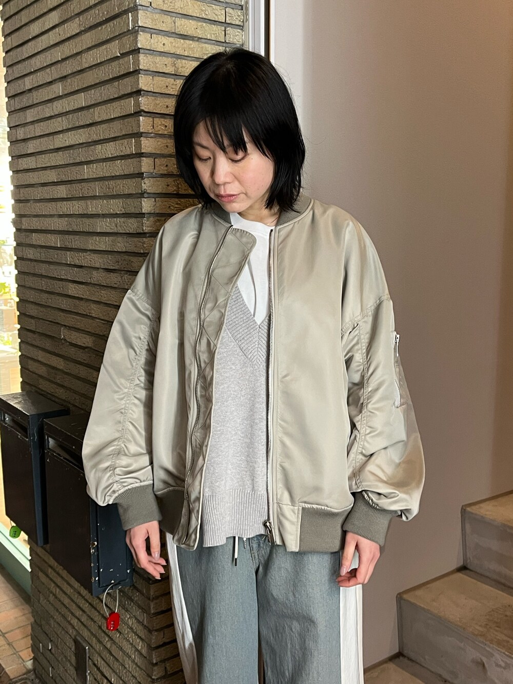 ベージュ系のMA-1、グレー系のTシャツ/カットソー、ブルー系のデニムパンツを着用したレディースの春コーディネートの2枚目の写真