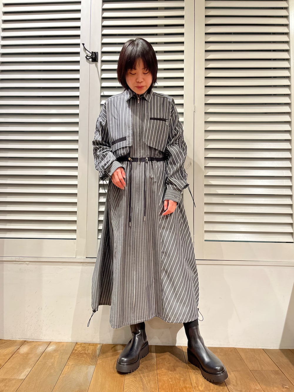 ブラック系のブルゾン、グレー系のワンピース、ブラック系のブーツを着用したレディースの冬コーディネートの2枚目の写真