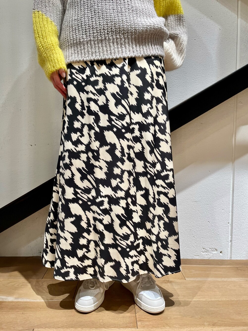 グレー系のバッグ、グレー系のニット/セーター、ブラック系のスカートを着用したレディースの秋コーディネートの5枚目の写真