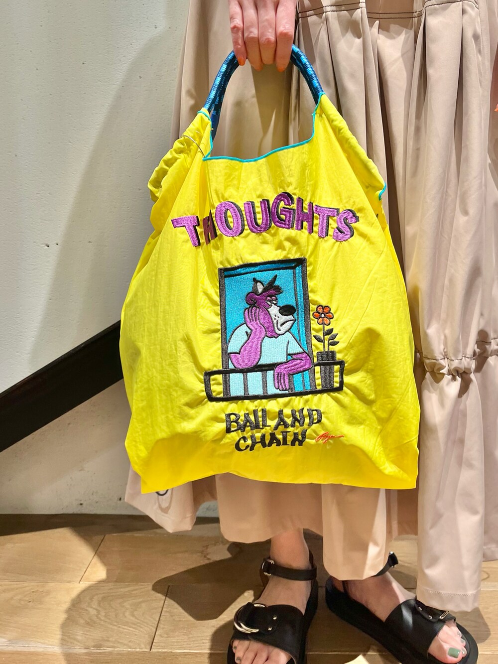 イエロー系のトートバッグ、グレー系のTシャツ/カットソー、ベージュ系のスカートを着用したレディースの夏コーディネートの3枚目の写真