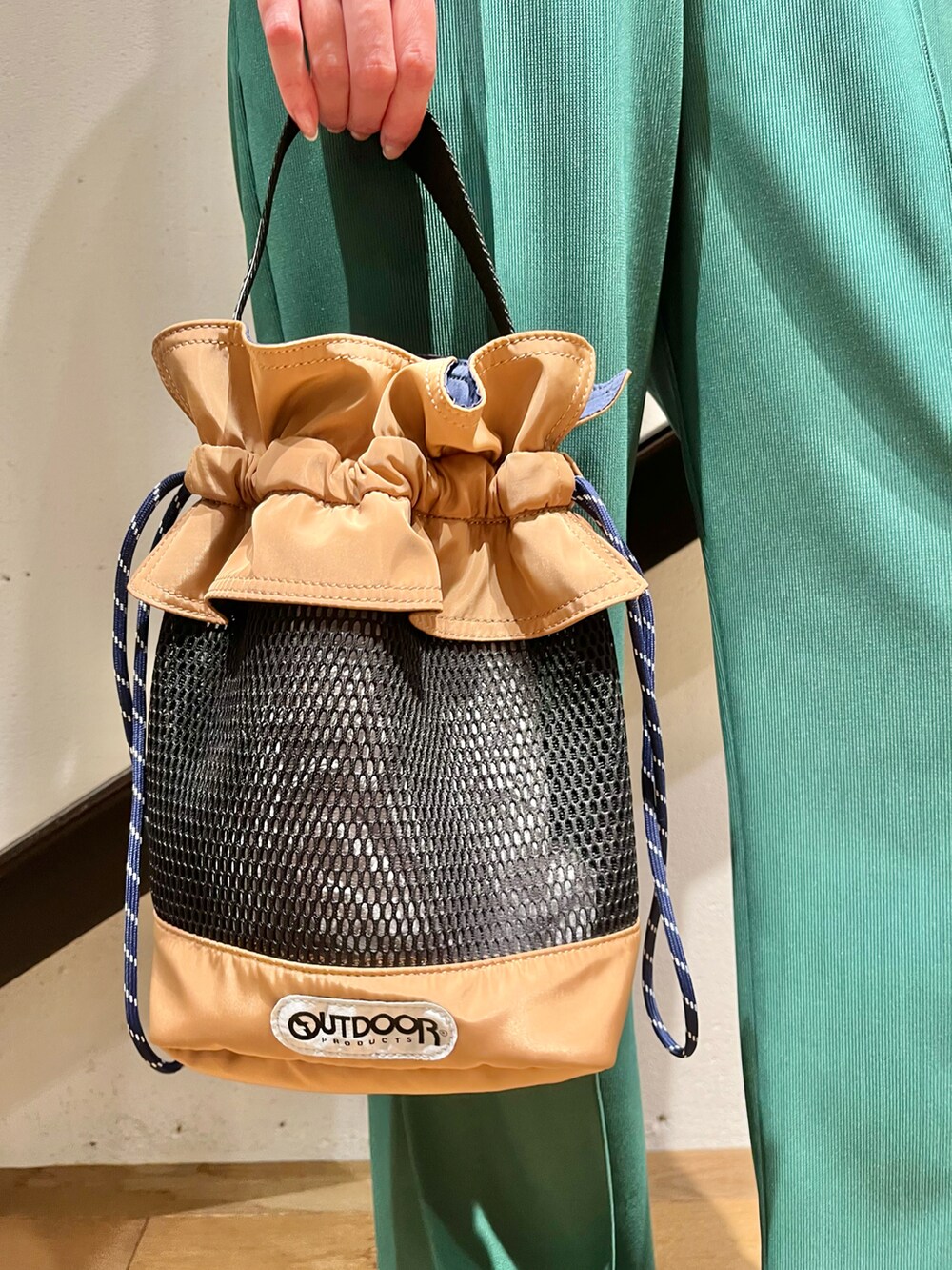 ブラック系のトップス、イエロー系のトートバッグ、グリーン系のパンツを着用したレディースの夏コーディネートの3枚目の写真