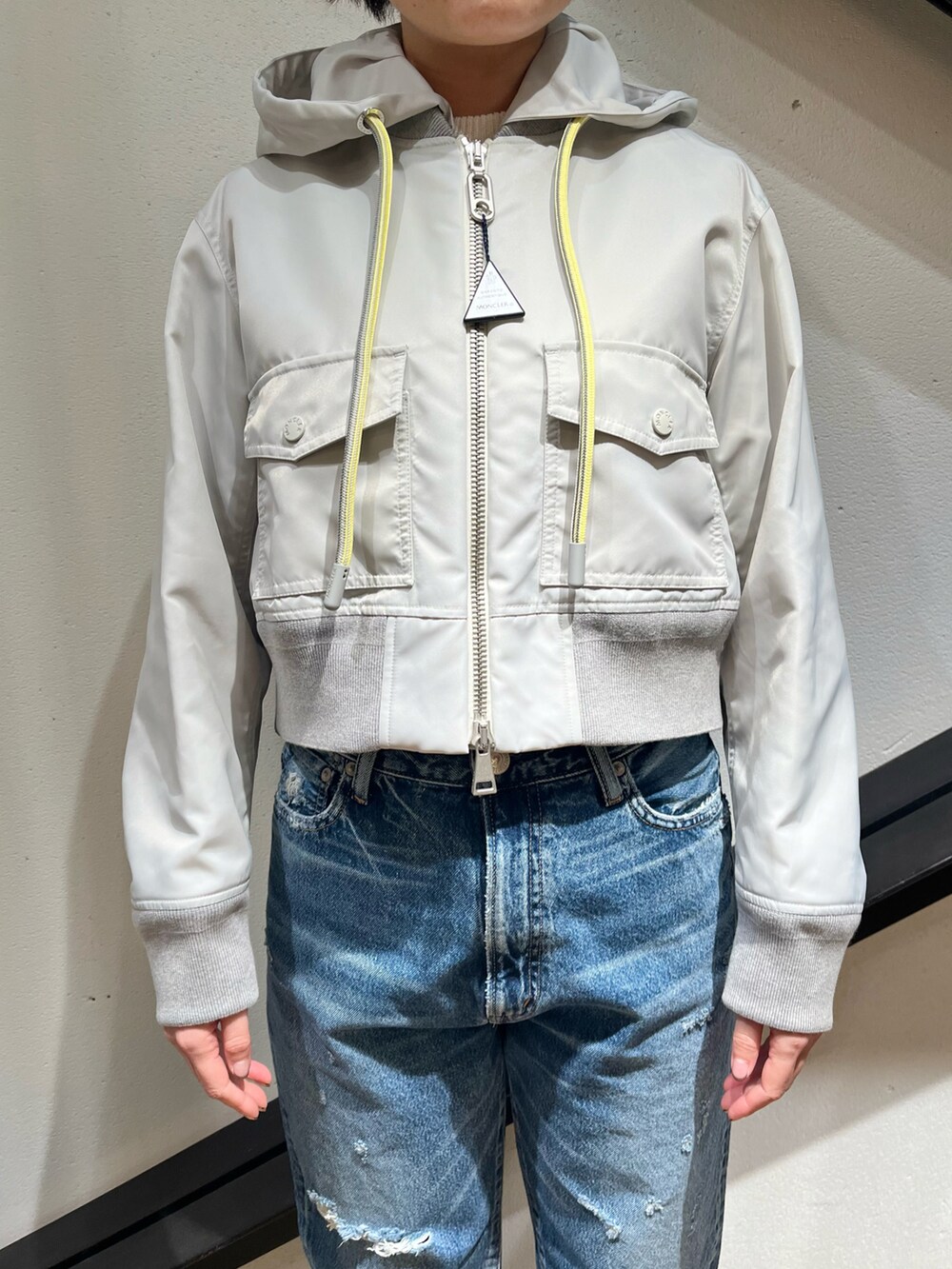 ホワイト系のトートバッグ、グレー系のブルゾン、ブルー系のデニムパンツを着用したレディースの春コーディネートの3枚目の写真