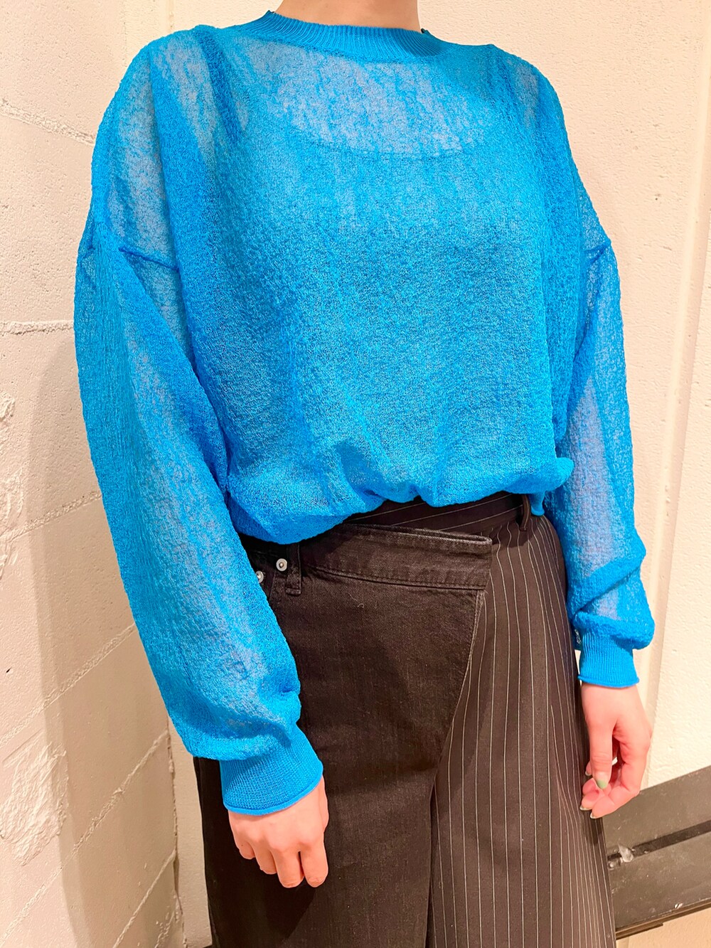 ブルー系のトップス、グレー系のベスト、ブラック系のバッグを着用したレディースの春コーディネートの4枚目の写真