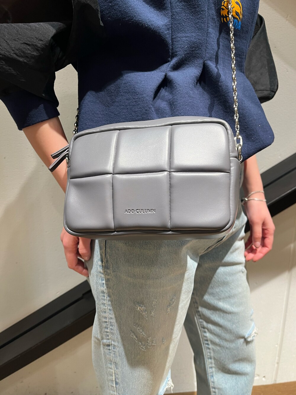 グレー系のショルダーバッグ、ブルー系のスウェット、ブルー系のデニムパンツを着用したレディースの春コーディネートの2枚目の写真