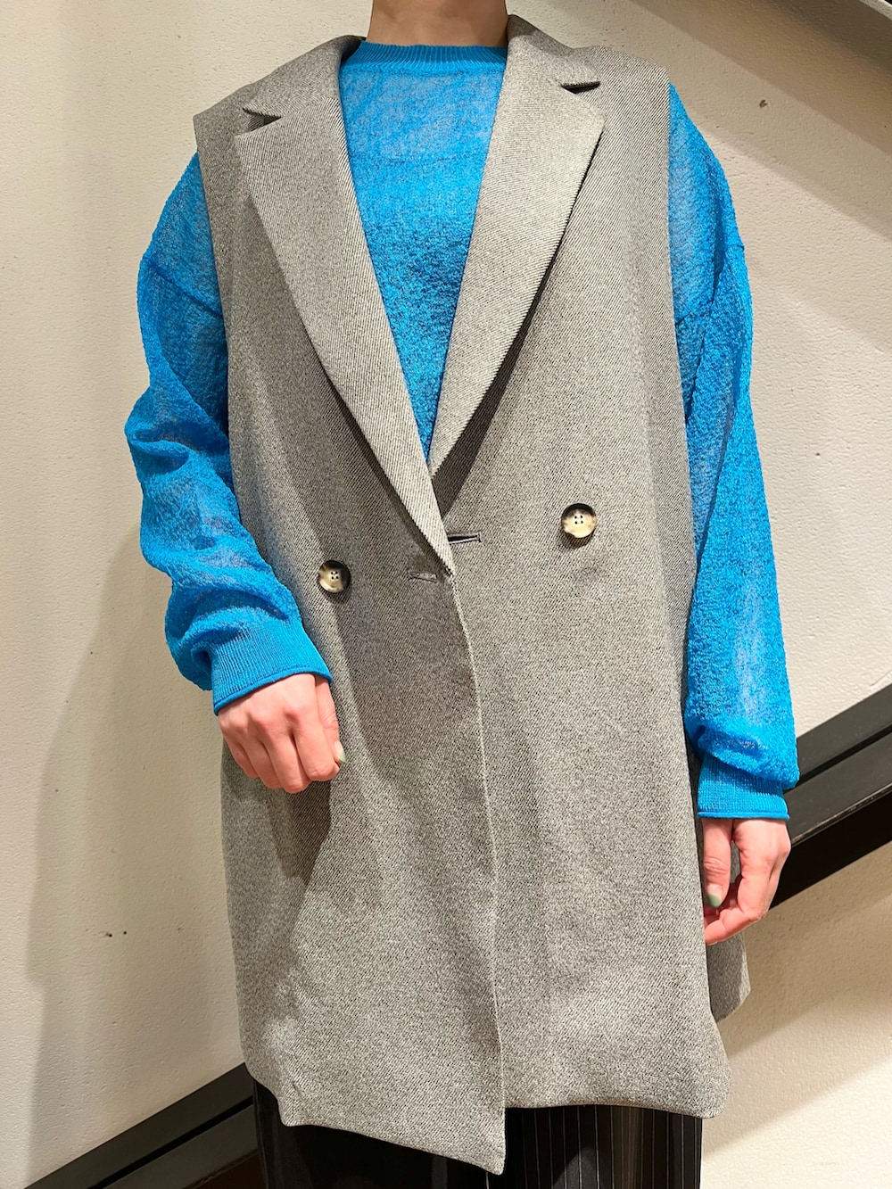 ブルー系のトップス、グレー系のベスト、ブラック系のバッグを着用したレディースの春コーディネートの3枚目の写真