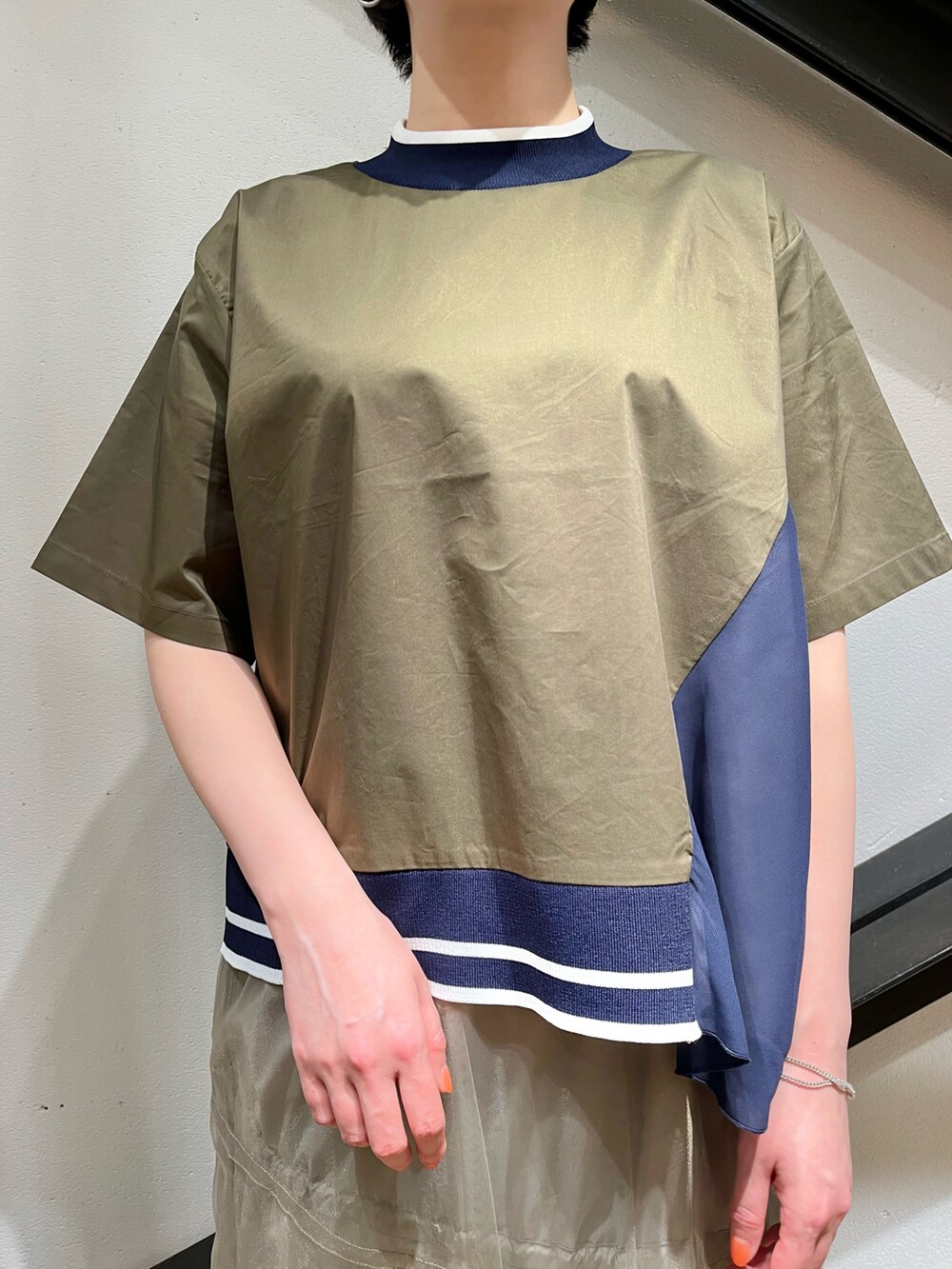 グリーン系のトップス、ゴールド系のスカート、ホワイト系のスニーカーを着用したレディースの春コーディネートの4枚目の写真