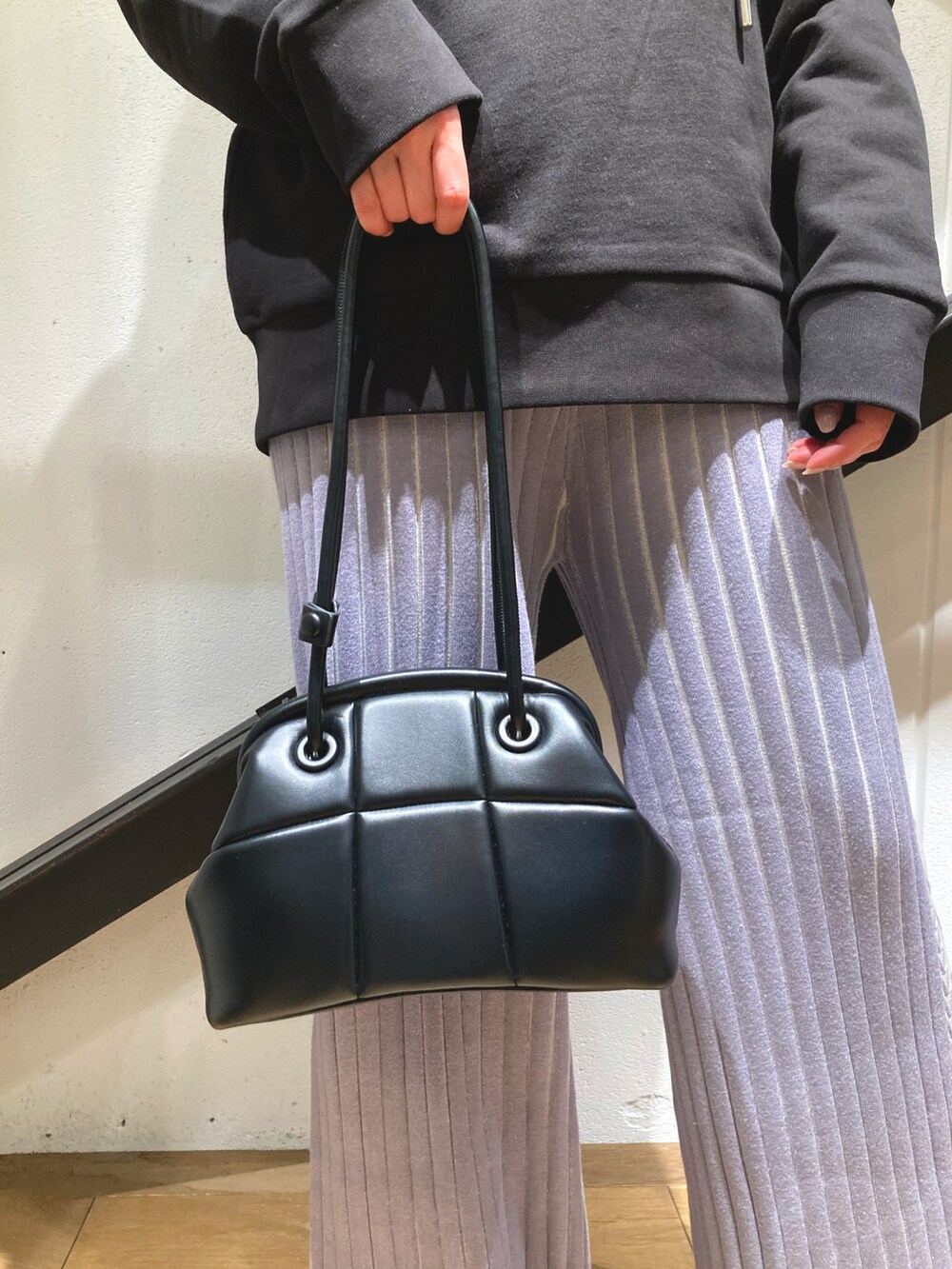 ブラック系のハンドバッグ、ブラック系のパーカー、グレー系のパンツを着用したレディースの春コーディネートの3枚目の写真