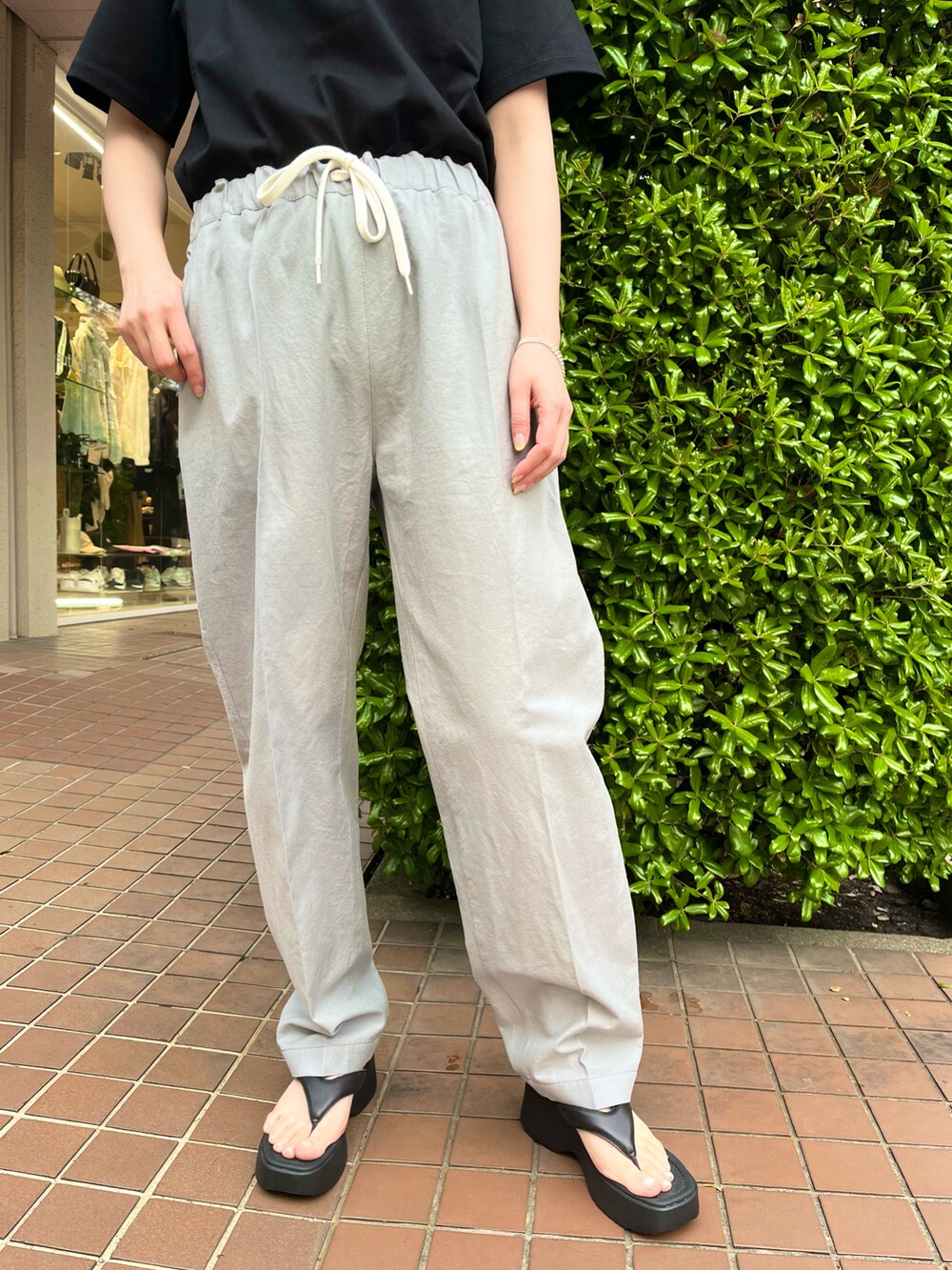 ブラック系のショルダーバッグ、ブラック系のTシャツ/カットソー、グレー系のパンツを着用したレディースの春コーディネートの4枚目の写真