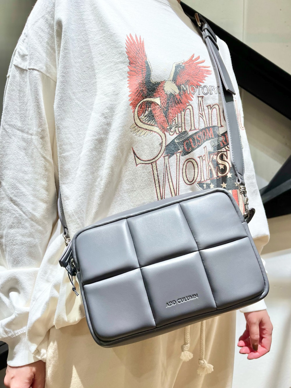 グレー系のショルダーバッグ、ホワイト系のTシャツ/カットソー、グレー系のスニーカーを着用したレディースの秋コーディネートの2枚目の写真