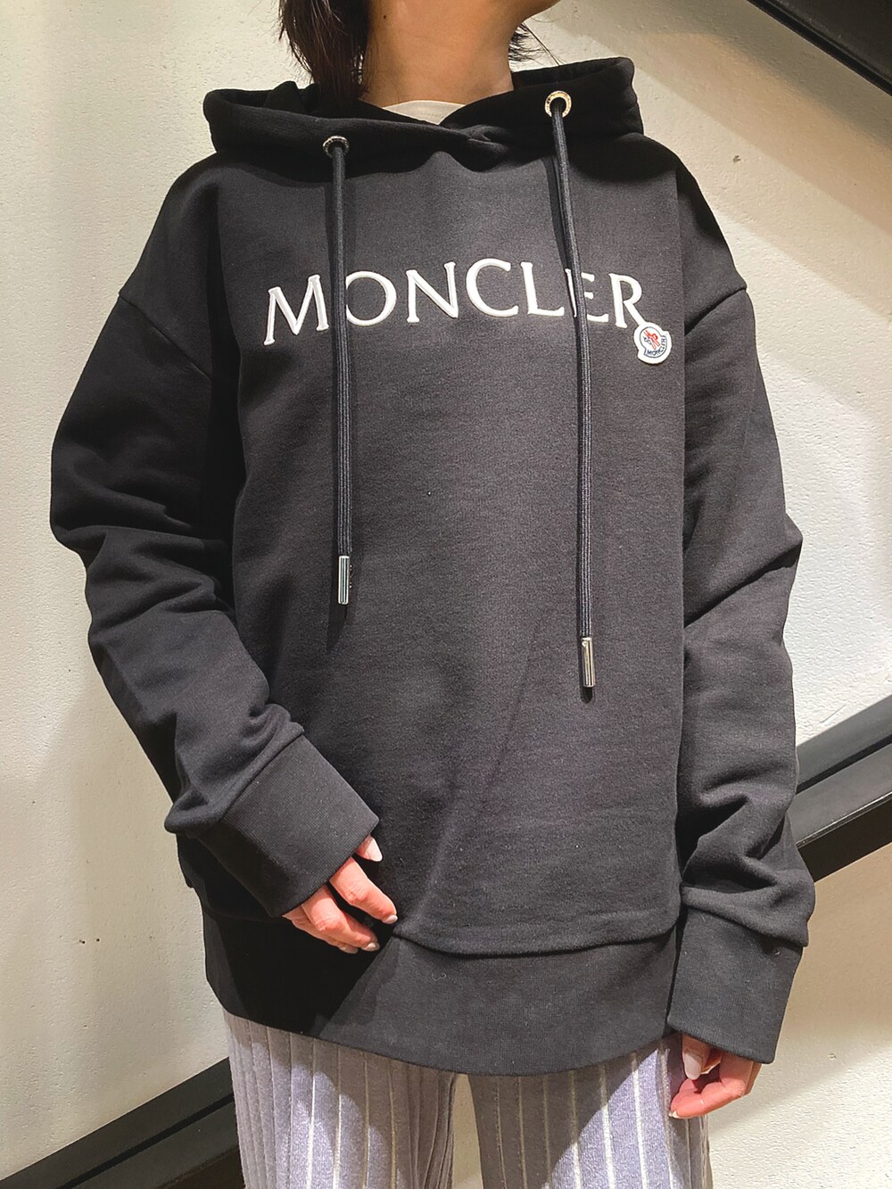 ブラック系のハンドバッグ、ブラック系のパーカー、グレー系のパンツを着用したレディースの春コーディネートの2枚目の写真