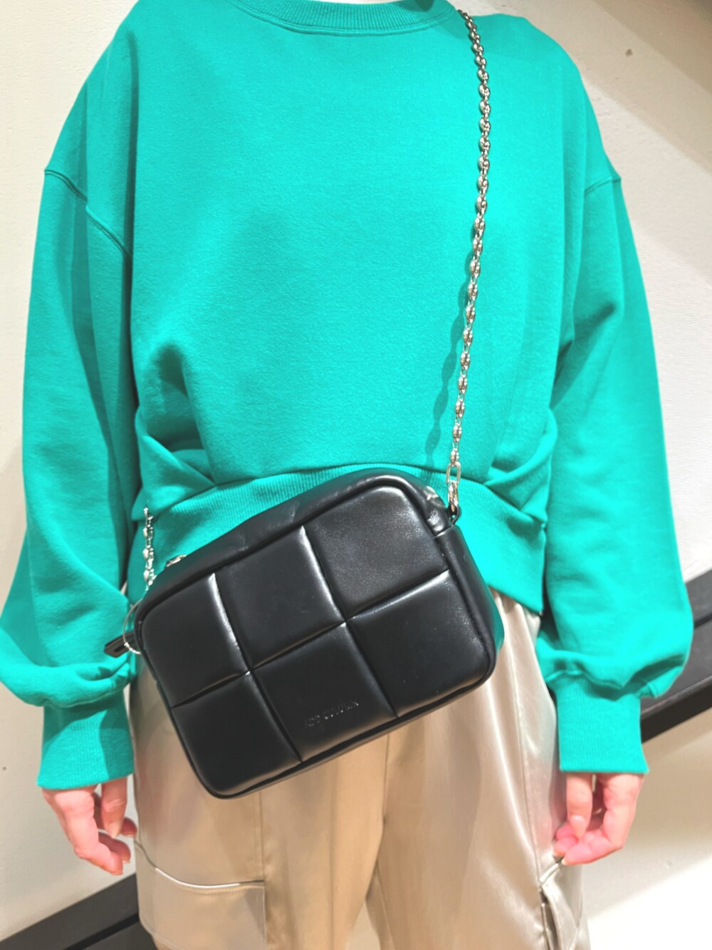 ブラック系のショルダーバッグ、グリーン系のスウェット、グレー系のパンツを着用したレディースの秋コーディネートの2枚目の写真