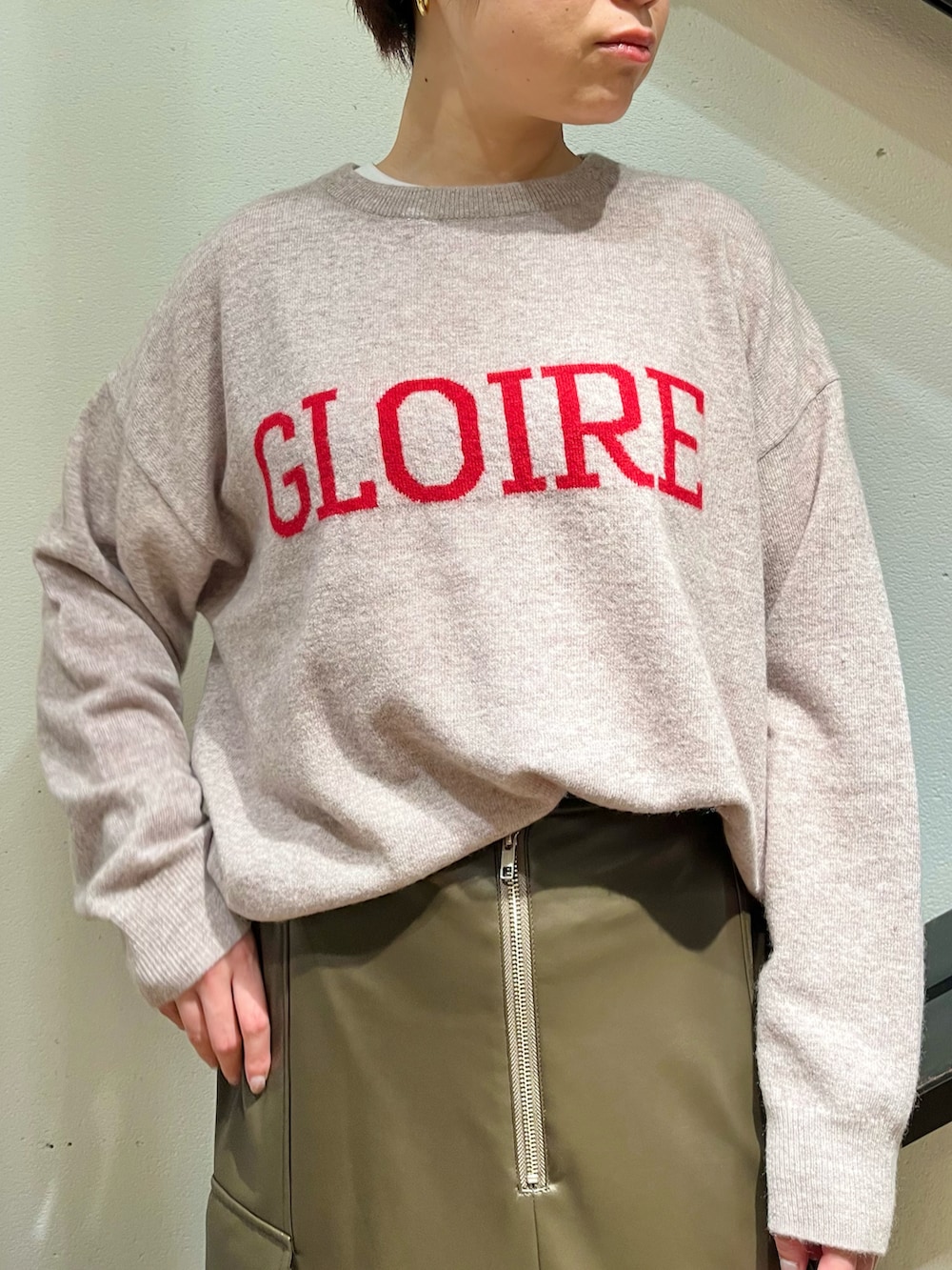 ブラック系のハンドバッグ、ホワイト系のピーコート、ベージュ系のニット/セーターを着用したレディースの冬コーディネートの2枚目の写真