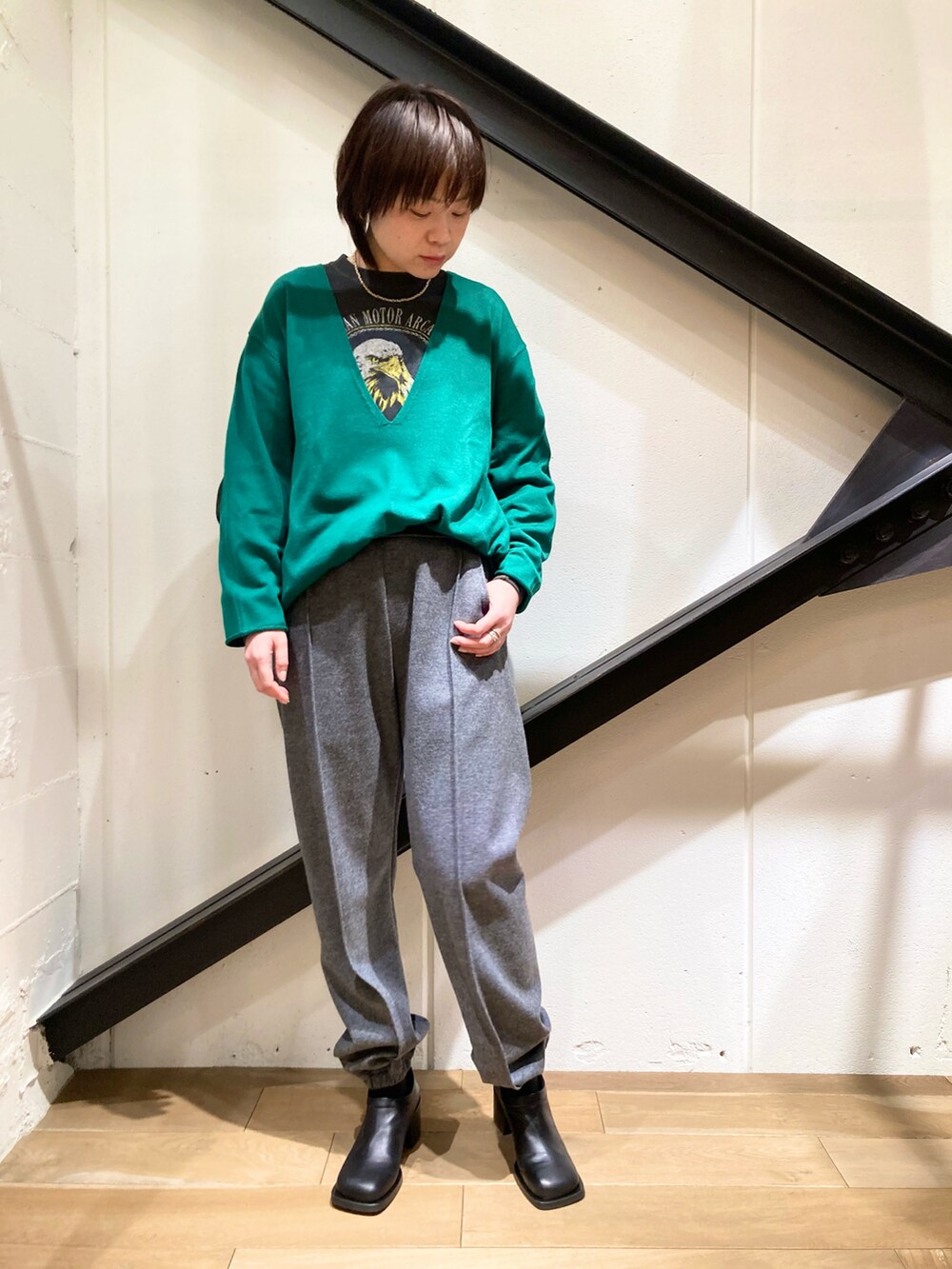 ブラック系のTシャツ/カットソー、グリーン系のニット/セーター、ベージュ系のトレンチコートを着用したレディースの冬コーディネートの2枚目の写真