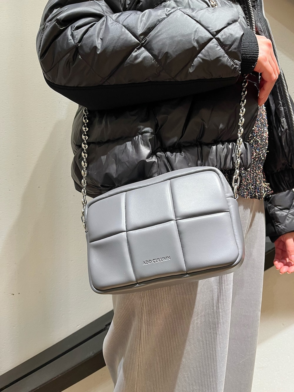 グレー系のショルダーバッグ、ブラック系のダウンジャケット/コート、ブラック系のニット/セーターを着用したレディースの冬コーディネートの2枚目の写真